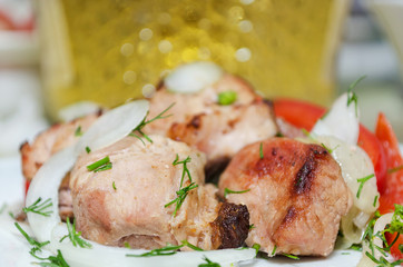 Pork kebab on plate with red pepper and onion on the background of bottles of wine. Selective focus