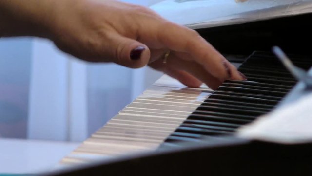 The pianist plays the piano. Hands of a woman playing music on a keyboard instrument. Fingers on the keys.