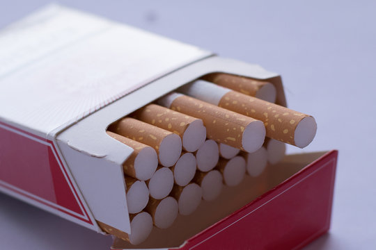 Cigarettes in an open red and white pack on a light table