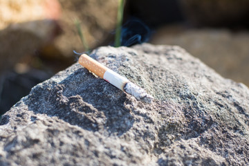 The cigarette butt is on the stone