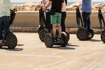 A group of people are riding on electric scooter with a sea view