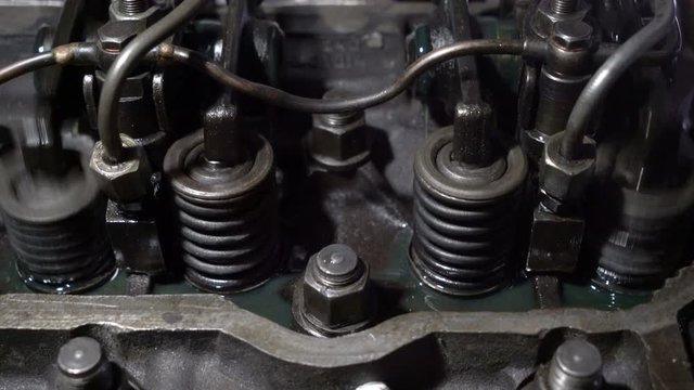 The mechanic adjusts the valve on the diesel engine.