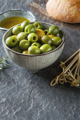 Olivier oil with fresh herbs and bread. Gray background. Italian and Greek national food.