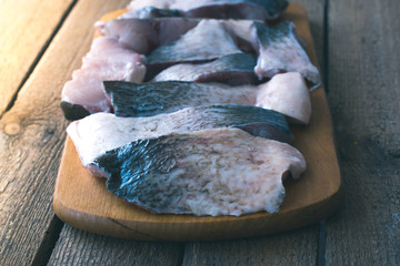 Raw fish cooking with spices on a wooden background.