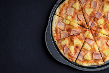 Pizza hawaii on dark stone background.