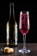 glass of pink sparkling champagne standing on a dark surface