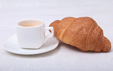 Crispy fresh croissants and cup of coffee espresso on a white background, morning breakfast, selective focus