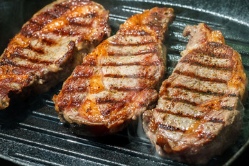 Raw Ribeye Steak with Herbs and Spices, frying on grill pan