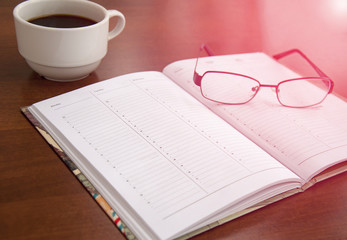 blank checklist on wooden table With coffee and glasses