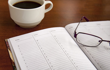 blank checklist on wooden table With coffee and glasses