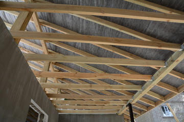 Wooden roof construction. house building. Installation of wooden beams at construction the roof truss system of the house. Installing the vapor barrier on the roof