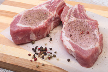 Raw pork chops, spices on cutting board. Ready for cooking.
