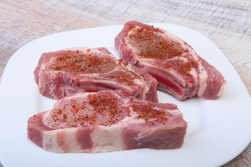 Raw pork chops, spices on cutting board. Ready for cooking.
