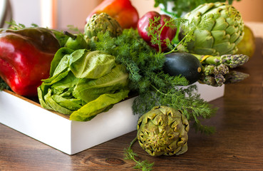 Variety of green vegetables and fruits in a crate on the table