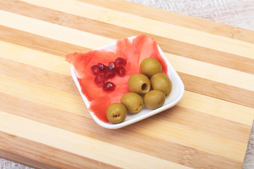 Plate with ginger, Olives, pomegranate on wooden background. Japanese cuisine. Asia food.
