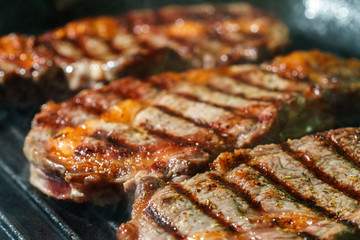 Raw Ribeye Steak with Herbs and Spices, frying on grill pan