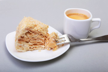 Homemade Napoleon puff cake on plate and traditional espresso coffee isolated on white background. close-up.