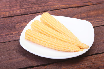 Mini Corn cob preserved on plate on wooden board.