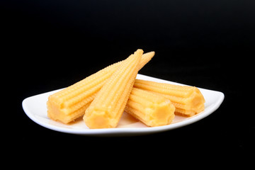 Mini Corn cob preserved on plate on wooden board.
