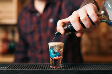 Handsome bearded barman is making cocktail in night club. 