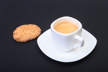 Classic espresso in white cup with homemade cake on black background. Selective focus.