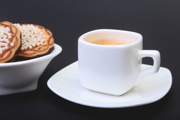 Classic espresso in white cup with homemade cake on black background. Selective focus.