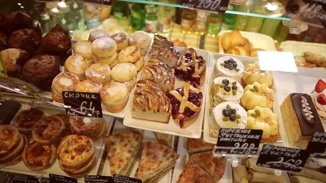 Shelf at a bakery with many different kinds of dessert - cakes, pastries, sweets,tarlets and pies.Wide assortment of fresh pastry at shop window.