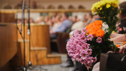 Audience in the concert hall holding flowers for artists on stage