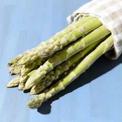 bundle of green asparagus, isolated on blue textured wooden background
