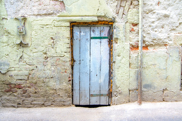 retro wooden door on a cracked concrete vintage brick wall background 