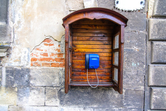 Retro telephone with wooden phone booth on a cracked concrete vintage stone wall background