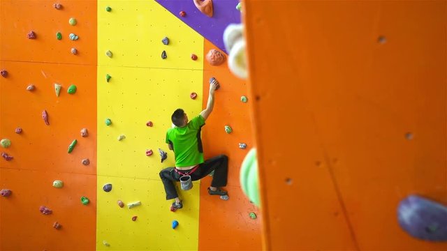 Young Man Climbing Up On Practice Wall In Gym