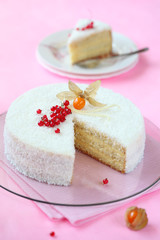 Coconut Orange Layered Cake on transparent round board, on light pink background.