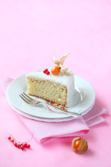 Piece of Coconut Orange Layered Cake on white plate, on light pink background.