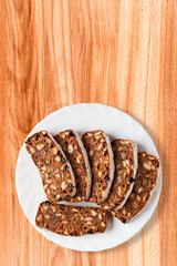 A white plate with a few slices of rye-wheat bread with nuts and dried fruits. A delicious and healthy snack. Closeup, top view