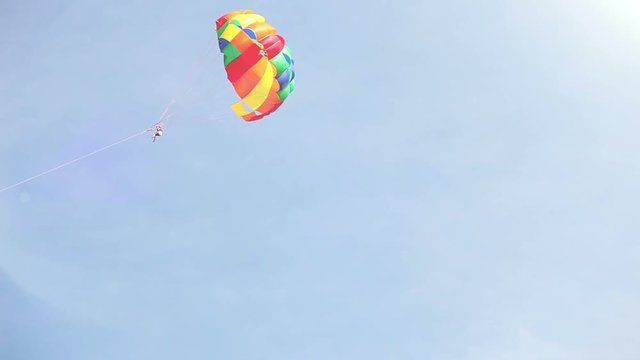 A multi-colored parachute flying in the sky tugged by a boat