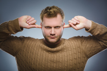 Closeup portrait of worried man covering his ears, observing. Hear nothing