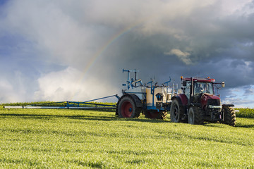 Obraz premium farm tractor carrying spraying chemicals on a spring field
