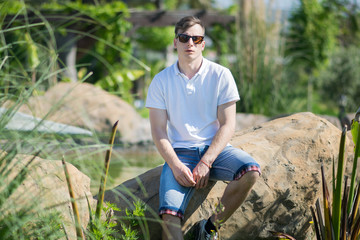 Cheerful young male model wearing white t-shirt in summer scenery