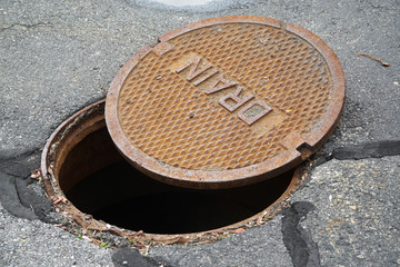 close up on opened rustic manhole cover on the street