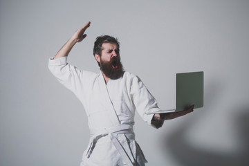 bearded shouting karate man in kimono with laptop