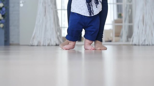 Mother and little boy walking on wood floor at home