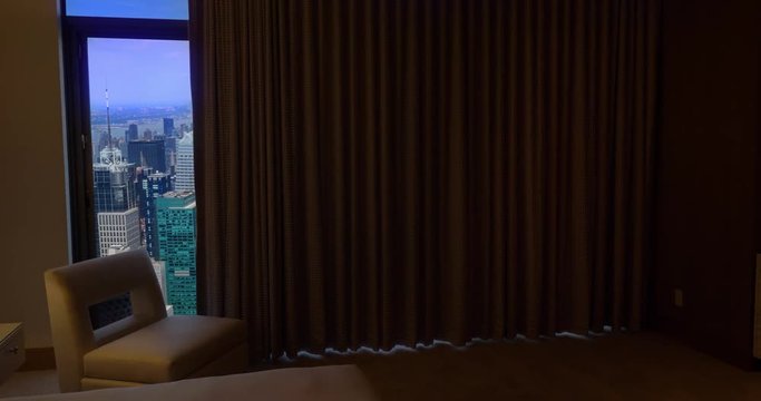 Bedroom curtains automatically open in an upscale New York City apartment to reveal the Manhattan skyline.	