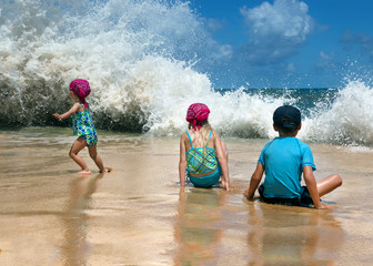 Children on the beach, a big wave, the child runs away in fright. Playa Los Tubos (Manati, Puerto Rico)