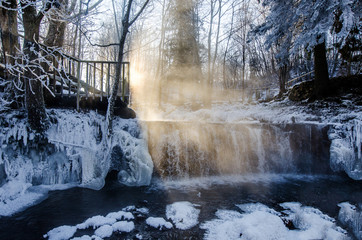 Winter landscape. Waterfall winter in the sunrise sunlight.