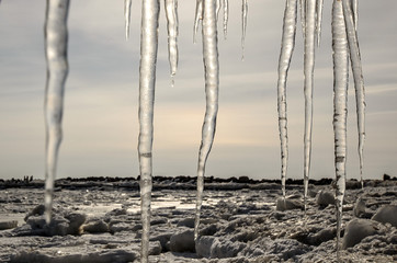 Cold winter landscape with frozen sea coast, ice and icicles.