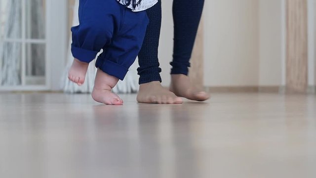 Mother and little boy walking on wood floor at home