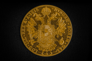 Close-up view of Austria-Hungary thaler, revers of golden coin-ducat from 1915 with Kaiser Franz Joseph I on dark background