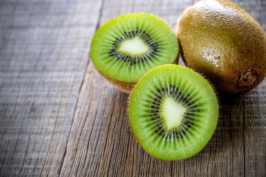 Fresh green healthy kiwi fruits and sliced on wooden table background