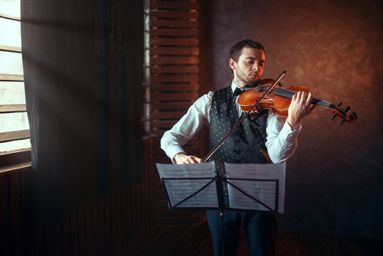 Male violinist playing classical music on violin